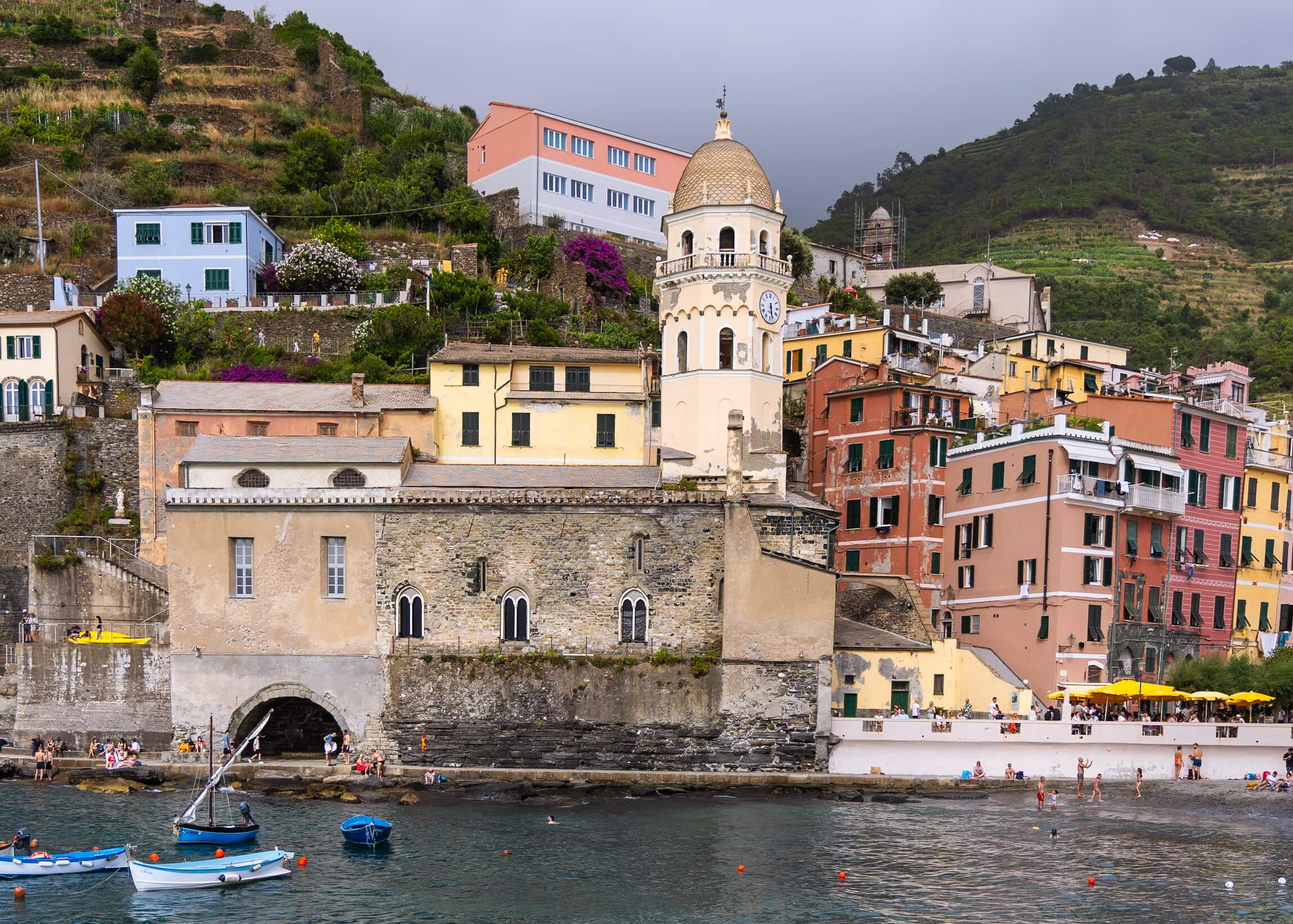 The iconic bell tower of the Church of Santa Margherita d'Antiochia in Vernazza, Cinque Terre, surrounded by pastel-colored buildings. The church overlooks the harbor, adding to the picturesque charm of the town. A must-visit landmark for travelers exploring Cinque Terre.